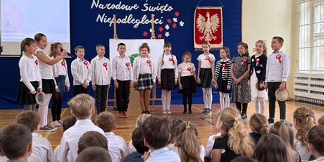 Powiększ grafikę: Uczniowie w sali gimnastycznej  podczas apelu wykonują utwór muzyczny.