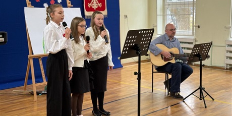 Powiększ grafikę: Uczennice  w sali gimnastycznej  podczas apelu wykonują utwór muzyczny.