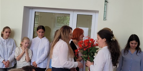 Powiększ grafikę: Uczniowie wręczają kwiaty nauczycielom w sali gimnastycznej.