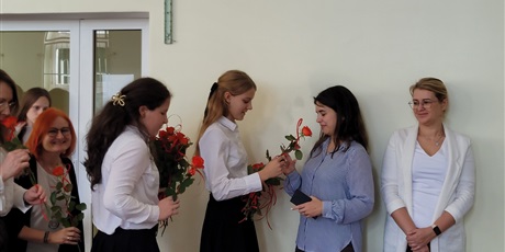 Powiększ grafikę: Uczniowie wręczają kwiaty nauczycielom w sali gimnastycznej.