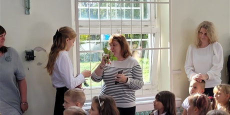 Powiększ grafikę: Uczniowie wręczają kwiaty nauczycielom w sali gimnastycznej.