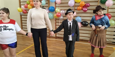 Powiększ grafikę: Uczniowie w przebraniach karnawałowych i nauczyciel podczas balu w sali gimnastycznej.