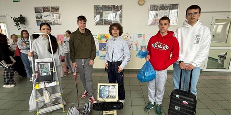 Powiększ grafikę: Uczniowie z nietypowymi plecakami na korytarzu szkolnym.