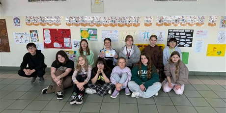 Powiększ grafikę: Zbiorowe zdjęcie uczniów  przy plakatach informujących o Dniu matematyki i liczby pi na korytarzu szkolnym.