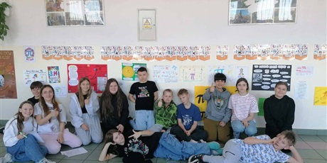 Powiększ grafikę: Zbiorowe zdjęcie uczniów  przy plakatach informujących o Dniu matematyki i liczby pi na korytarzu szkolnym.