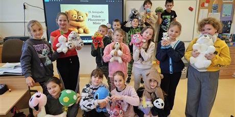 Powiększ grafikę: Zbiorowe zdjęcie uczniów z pluszowymi maskotkami w sali lekcyjnej.