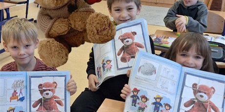 Powiększ grafikę: Uczniowie prezentują prace plastyczne z misiami.