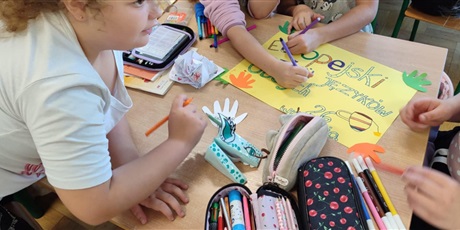 Powiększ grafikę: Uczniowie w sali lekcyjnej przygotowują plakaty.