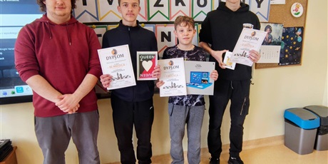 Powiększ grafikę: Opiekun oraz uczniowie z nagrodami i dyplomami za konkurs w sali lekcyjnej.