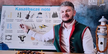 Powiększ grafikę: Mężczyzna w stroju kaszubskim prezentuje alfabet kaszubski