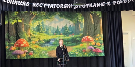 Powiększ grafikę: Uczestniczka konkursu podczas recytacji wiersza na scenie.