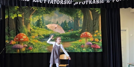 Powiększ grafikę: Uczestniczka konkursu podczas recytacji wiersza na scenie.