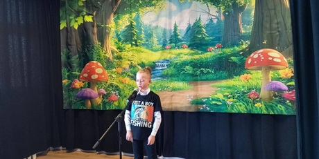 Powiększ grafikę: Uczestnik konkursu podczas recytacji wiersza na scenie.