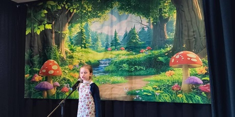 Powiększ grafikę: Uczestniczka konkursu podczas recytacji wiersza na scenie.