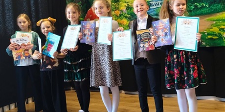 Powiększ grafikę: Zbiorowe zdjęcie uczestników konkursu z dyplomami i nagrodami na scenie.