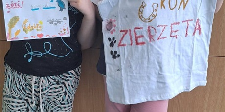 Powiększ grafikę: Uczniowie prezentują wykonane przez siebie koszulki z zapisanymi trudnymi słowami w sali lekcyjnej.