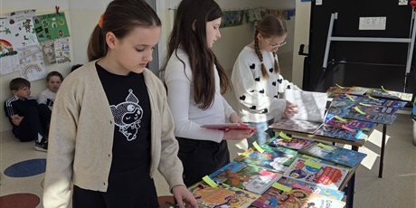 Powiększ grafikę: Uczennice oglądają książki na kiermaszu na korytarzu szkolnym.