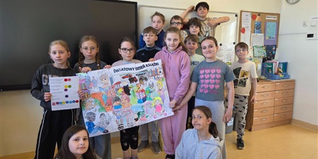 Powiększ grafikę: Uczniowie prezentują wykonany plakat "Światowy Dzień Książki" i listę lektur w sali lekcyjnej.