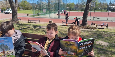 Powiększ grafikę: Uczniowie czytają książki na patio szkolnym.