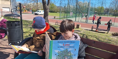 Powiększ grafikę: Uczniowie czytają książki na patio szkolnym.