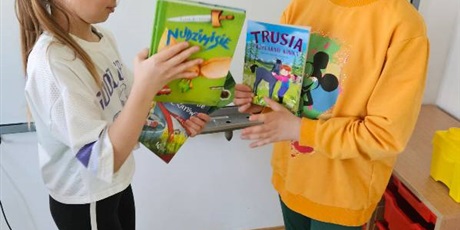 Powiększ grafikę: Uczennice wymieniają się książkami w sali lekcyjnej.