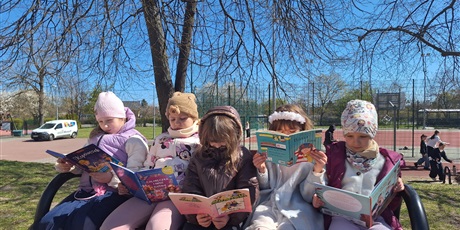 Powiększ grafikę: Uczniowie czytają książki na patio szkolnym.