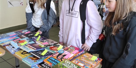 Powiększ grafikę: Uczennice oglądają książki na kiermaszu na korytarzu szkolnym.