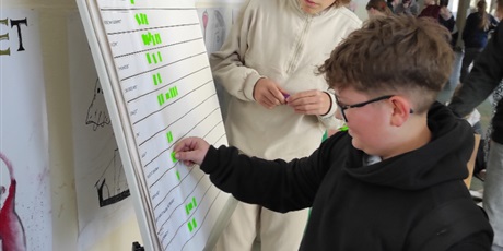 Powiększ grafikę: Uczeń oddaje swój głosy na najciekawsze książki na korytarzu szkolnym.