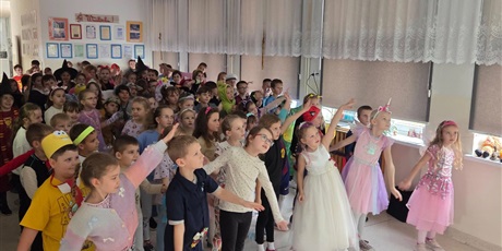 Powiększ grafikę: Uczniowie w przebraniach  za postacie z bajek na korytarzu szkolnym podczas tańca.