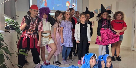 Powiększ grafikę: Zbiorowe zdjęcie uczniów przebranych  za postacie z bajek na korytarzu szkolnym.