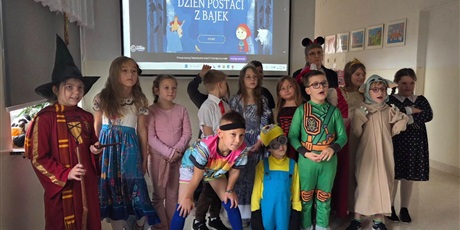 Powiększ grafikę: Zbiorowe zdjęcie uczniów przebranych  za postacie z bajek na korytarzu szkolnym.