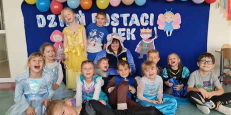 Powiększ grafikę: Zbiorowe zdjęcie uczniów i nauczyciela  przebranych za postacie z bajek w sali lekcyjnej.
