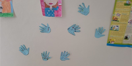 Powiększ grafikę: Plakaty i niebieskie "łapki" umieszczone na korytarzu szkolnym dotyczące praw dziecka.