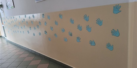 Powiększ grafikę: Niebieskie "łapki" umieszczone na korytarzu szkolnym z wypisanymi prawami dziecka.