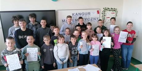 Powiększ grafikę: Zbiorowe zdjęcie uczestników konkursu z dyplomami w sali lekcyjnej.