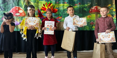 Powiększ grafikę: Uczestnicy konkursu z dyplomami i nagrodami na scenie.