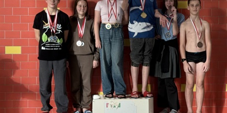 Powiększ grafikę: Uczniowie z medalami na podium na pływalni.