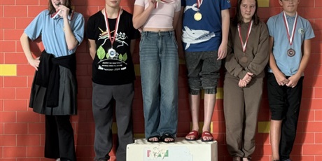 Powiększ grafikę: Uczniowie z medalami na podium na pływalni.
