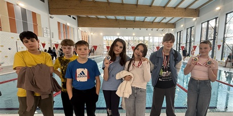 Powiększ grafikę: Uczniowie z medalami  na pływalni.