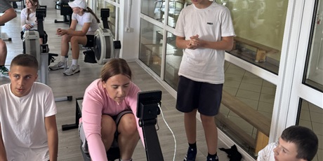 Powiększ grafikę: Uczniowie wiosłujący na  ergometrze wioślarskim podczas zawodów.