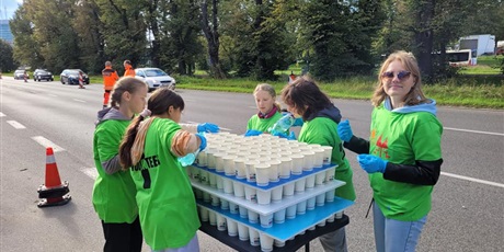 Powiększ grafikę: Uczniowie i nauczyciel podczas przygotowania napoi dla uczestników półmaratonu.