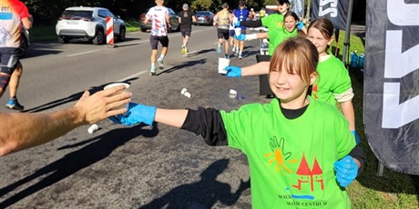 Powiększ grafikę: Uczniowie podający napoje uczestnikom półmaratonu.
