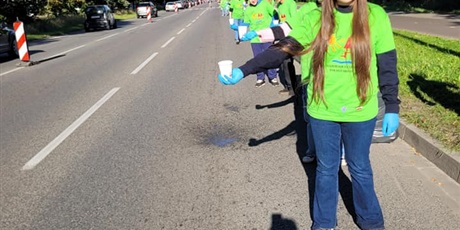 Powiększ grafikę: Uczniowie podający napoje uczestnikom półmaratonu.