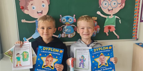 Powiększ grafikę: Dwóch uczniów w sali lekcyjnej z upominkami i dyplomami  z okazji dnia chłopaka.