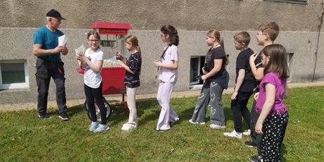 Powiększ grafikę: Dzieci czekające  w kolejce na popcorn na patio szkolnym