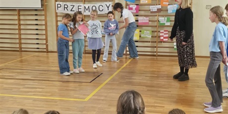 Powiększ grafikę: Uczennice demonstrują wykonane prace podczas apelu w sali gimnastycznej.