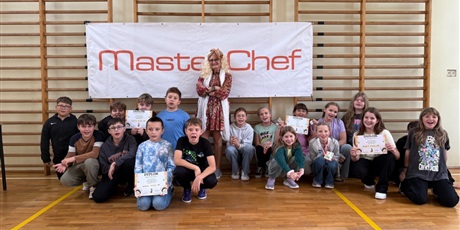 Powiększ grafikę: Zbiorowe zdjęcie uczestników konkursu kulinarnego z jurorką w sali gimnastycznej.