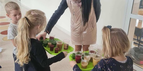 Powiększ grafikę: Uczniowie częstują nauczycielkę zdrowymi koktajlami na korytarzu szkolnym.