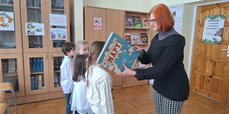 Powiększ grafikę: Wicedyrektor  i uczniowie podczas pasowania na czytelnika w bibliotece.