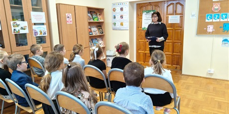 Powiększ grafikę: Uczniowie i nauczyciel podczas pasowanie na czytelnika w bibliotece.